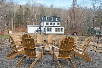 a group of chairs and a table with a house in the background at Pine Hill Chateau - Ski Belleayre, Hunter Mountain in Pine Hill
