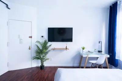 a bedroom with a bed and a desk and a tv on the wall at 83-2FE UES Central Park Newly Furnished Studio in New York