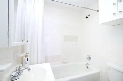 a white bathroom with a sink and a bath tub at 83-2FE UES Central Park Newly Furnished Studio in New York