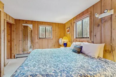 a bedroom with a bed with wooden walls and windows at Farmhouse on the Road in Wilmington