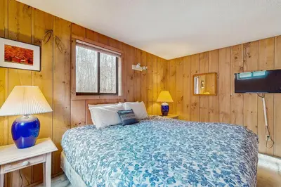 a bedroom with a bed with wooden walls and a tv at Farmhouse on the Road in Wilmington