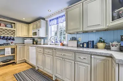 a kitchen with white cabinets and a large window at Lakefront Home, Close to Mt Southington! in Wolcott