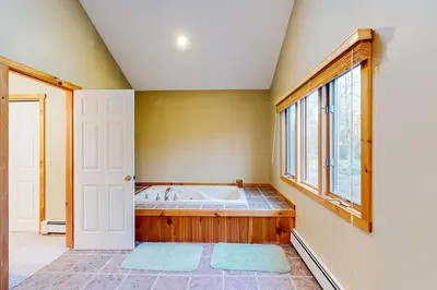 a large bathroom with a tub and a window at Wooded Wonder in West Dover