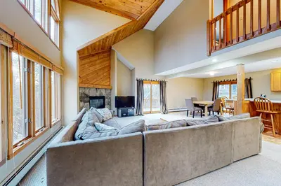 a living room with a large couch and a fireplace at Wooded Wonder in West Dover