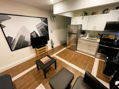 a kitchen with white cabinets and a living room at 2 Bedrooms Flat 5 minutes from TIMES SQUARE in Long Island City