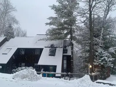 a house covered in snow with a tree at Fantastic 2 family vacation home with EV charger in Windham
