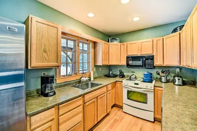 a kitchen with wooden cabinets and a white stove top oven at West Dover Home with Deck about 2 Mi to Mount Snow! in West Dover
