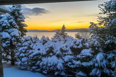 a snow covered forest with the sunset in the background at Hudson River Views Briarcliff Manor Home with Deck in Briarcliff Manor