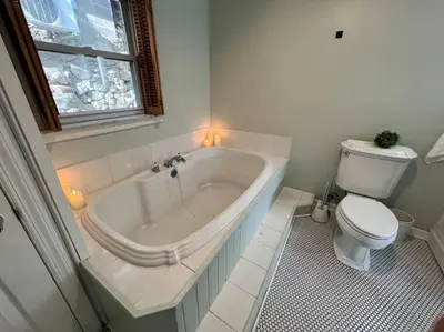 a white bathroom with a tub and a toilet at Cozy Cabin on the Lake w/ HotTub in Hopatcong