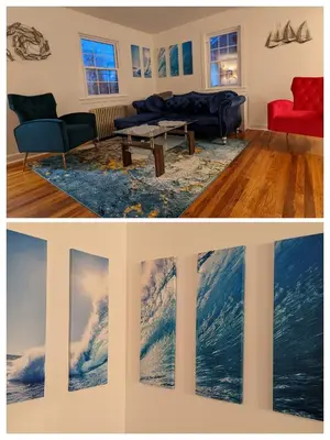 a living room with a painting of a wave at Live the Walkable Darien Lifestyle in this Charming Noroton Heights Gem! in Darien