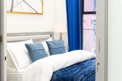 a bed with blue and white pillows and a window at 317-4A NEW Modern 1BR W&D Walk to Central Park in New York