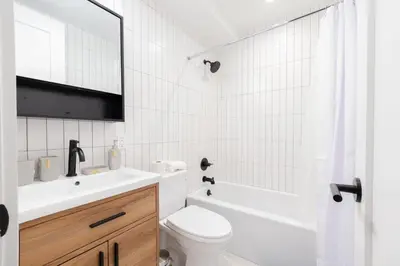 a white bathroom with a toilet and a sink and a tub at 323-2 Specious 2BR Williamsburg in Brooklyn