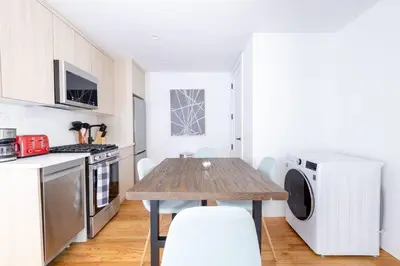 a kitchen with a wooden table in a kitchen with a washing machine at 323-2 Specious 2BR Williamsburg in Brooklyn