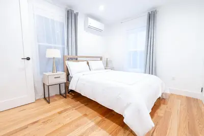 a white bedroom with a white bed and a wooden floor at 323-1 Specious 2BR Williamsburg in Brooklyn