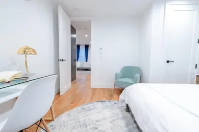 a white bedroom with a desk and a blue chair at 323-1 Specious 2BR Williamsburg in Brooklyn