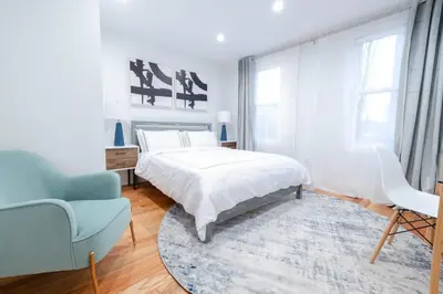 a white bedroom with a bed and a blue chair at 323-1 Specious 2BR Williamsburg in Brooklyn