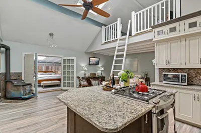 a kitchen with a stove top oven next to a living room at Guilford Carriage House at Granite Lodge! in Guilford