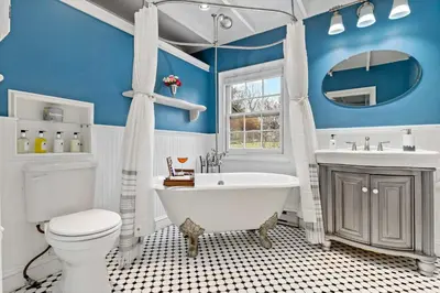 a blue bathroom with a tub and a toilet and a sink at Guilford Carriage House at Granite Lodge! in Guilford