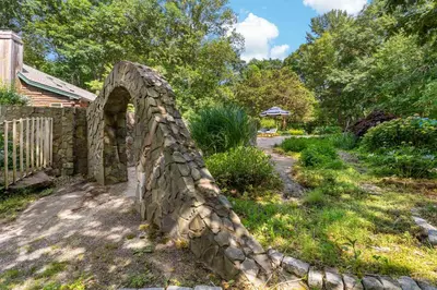 a stone bridge in a yard next to a fence at Guilford Carriage House at Granite Lodge! in Guilford