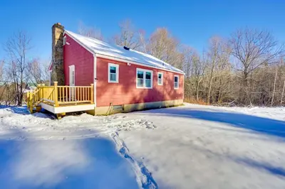 a red house in the snow next to a driveway at Cozy Southern Vermont Home with On-Site Trails in Whitingham