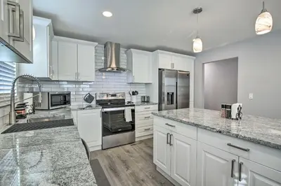 a kitchen with white cabinets and marble counter tops at Modern Middletown Retreat, Minutes to Downtown! in Middletown