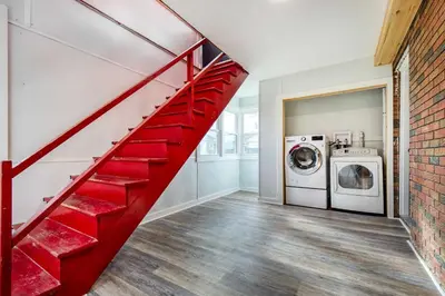 a red staircase in a laundry room with a washer and dryer at Modern Middletown Retreat, Minutes to Downtown! in Middletown