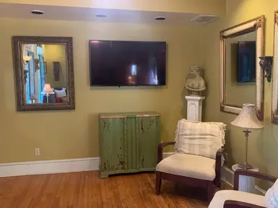 a living room with a tv and a chair and a mirror at A Bonnie Place in Oneonta