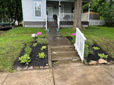 a house with a porch with a white fence and some flowers at A Bonnie Place in Oneonta