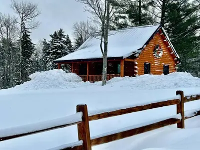 a log cabin in the snow with a fence at Florida Mountain Log Cabin in Florida