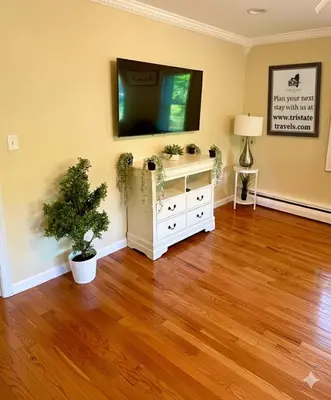 a living room with a television and a wooden floor at Forest and River Side Tranquil House in Montague