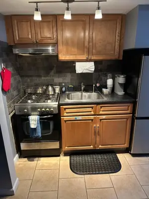 a kitchen with wooden cabinets and a stove and a sink at Morris Park area(very close to Jacobi Hospital in Morris Park