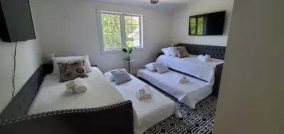 a room with two beds and a television in it at Hilltop Mansion at Rebecca's Fountain in Niskayuna