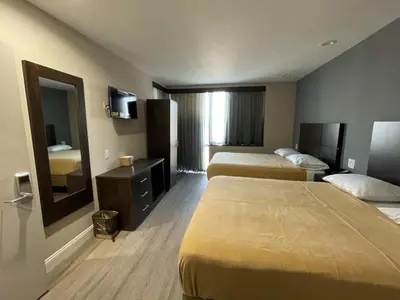 a hotel room with two beds and a mirror at Royal Hotel Bronx in Bronx
