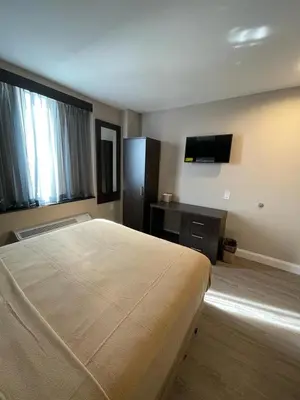 a bedroom with a large bed and a television at Royal Hotel Bronx in Bronx