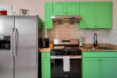 a green kitchen with green cabinets and a refrigerator at Peachy Paradise in East Rock Near DT/Yale in New Haven