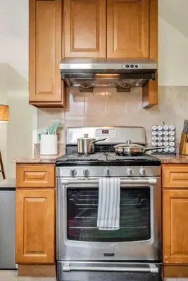a kitchen with a stainless steel stove and wooden cabinets at Golden Gem in Heart of East Rock Quiet 3BR Near DT and Yale in New Haven