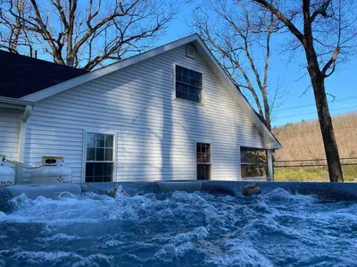 a white house with snow in front of it at Cozy Cottage, Hot Tub, Fire Pit, 15min to Hudson and hiking in Catskill