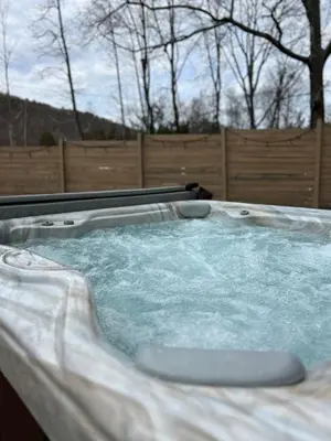 a jacuzzi tub in a backyard with a fence at Cozy Cottage, Hot Tub, Fire Pit, 15min to Hudson and hiking in Catskill