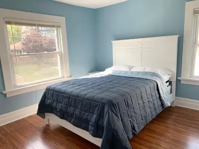 a bedroom with a bed with blue walls and a window at Newly renovated 4 bedroom apartment near downtown. in Montclair