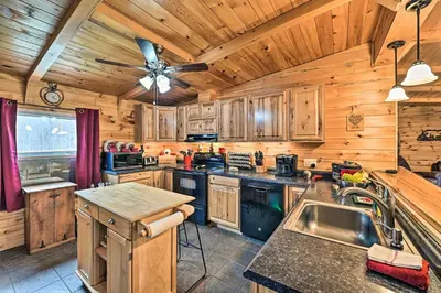 a kitchen with wooden cabinets and a ceiling fan at Otego Home with Hot Tub Near All Star Village! in Oneonta