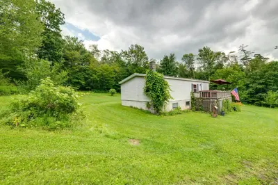 a white house in a field with a yard at Otego Home with Hot Tub Near All Star Village! in Oneonta