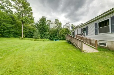 a house with a wooden deck next to a yard at Otego Home with Hot Tub Near All Star Village! in Oneonta