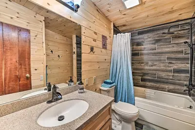 a bathroom with a sink and a toilet and a tub at Otego Home with Hot Tub Near All Star Village! in Oneonta