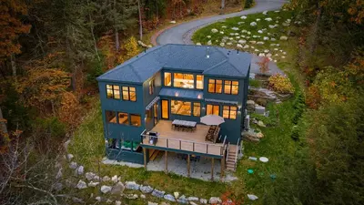 an aerial view of a large blue house with a deck at Forget-Me-Not by AvantStay Bold Lakefront Escape in Monterey
