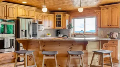 a kitchen with wooden cabinets and a large island with stools at Chester by AvantStay Amazing Views Secluded Home A True City Escape in Austerlitz