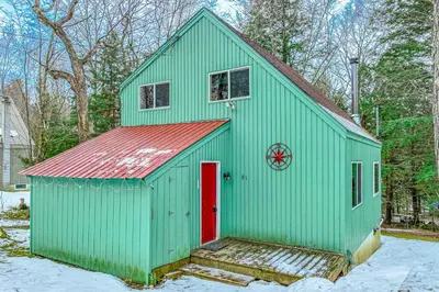 a green barn with a red door in the snow at Mowing Way Retreat in Wilmington