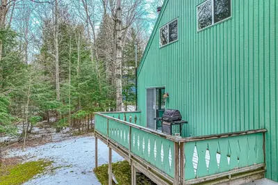 a green house with a balcony with a grill on it at Mowing Way Retreat in Wilmington