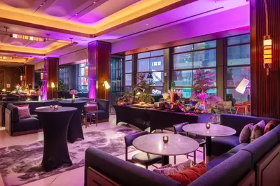 a restaurant with purple lighting and couches and tables at Tempo By Hilton New York Times Square in New York