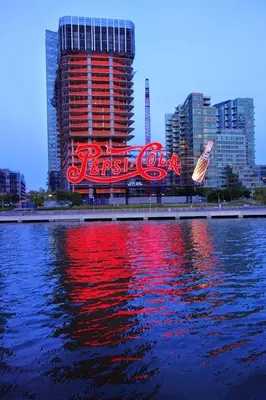 a large neon cola sign in front of a city at Bedroom 10 mins to Times Square! and is first floor in Queens