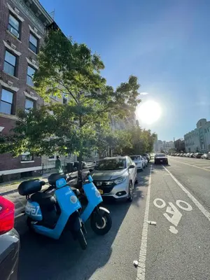a blue scooter parked on the side of a street at Bedroom 10 mins to Times Square! and is first floor in Queens